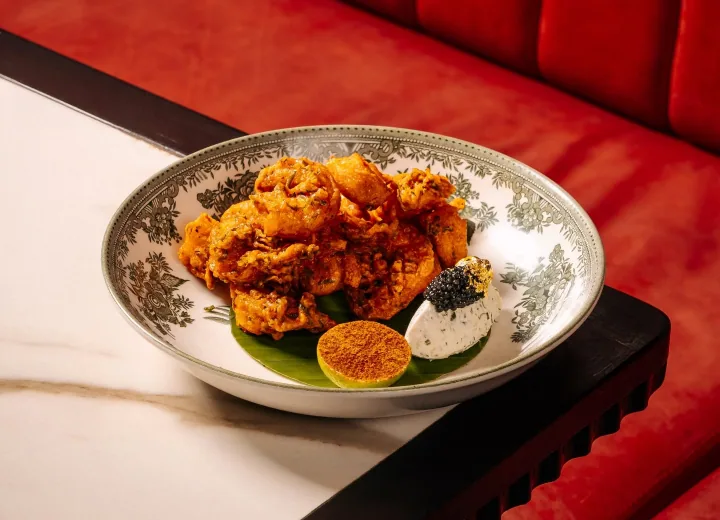 Crisp golden fritters in a patterned bowl on red velvet