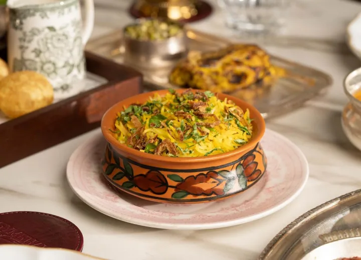 A hand-painted dish of saffron biryani on a silver platter