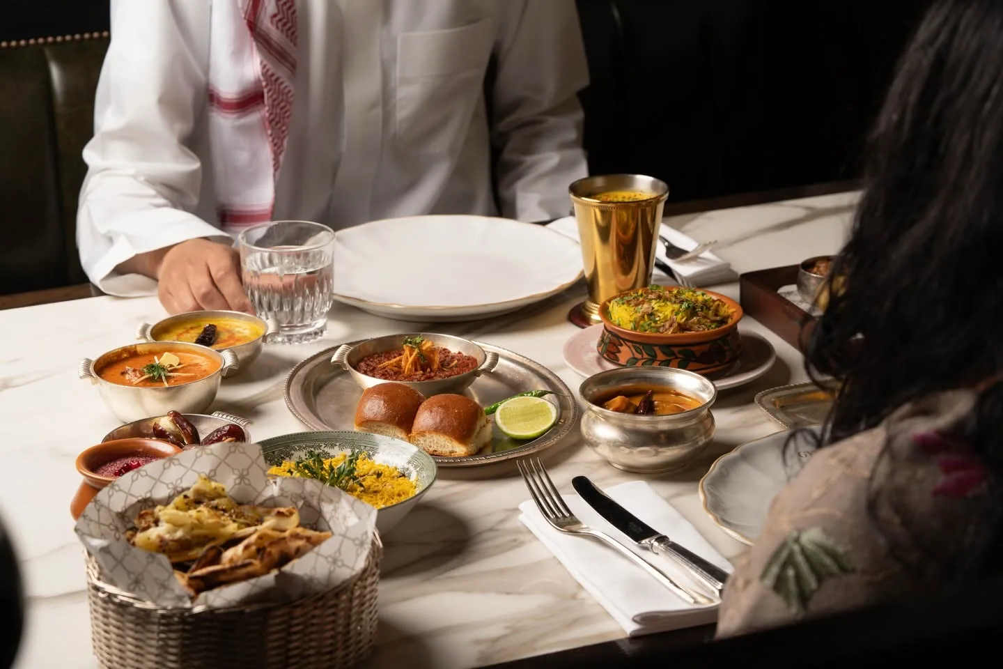 Diners sharing a spread of Indian dishes across a marble table